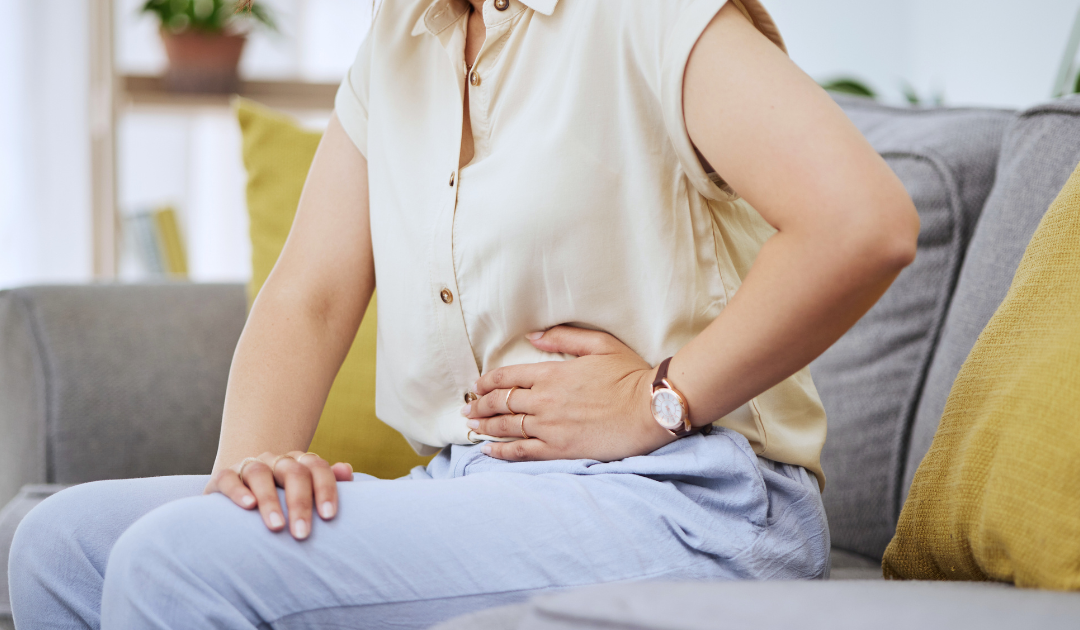 " a woman experiencing stomach cramps and bloating"