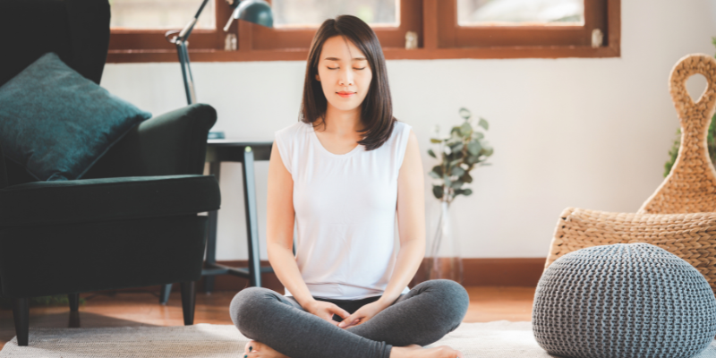 a girl sitting at home with eyes closed and meditating