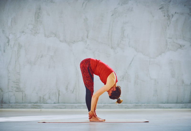 a girl folding forward and bending into forward folding pose or uttanasana