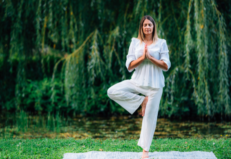 a girl doing tree pose outdoors