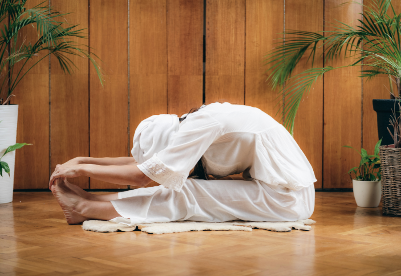 a girl doing seated forward fold- paschimottanasana