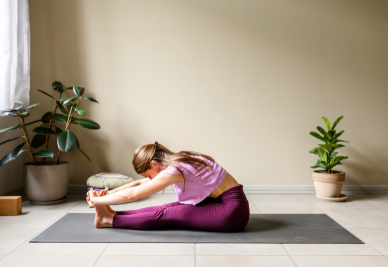 a girl doing paschimottanasana or seated forward fold