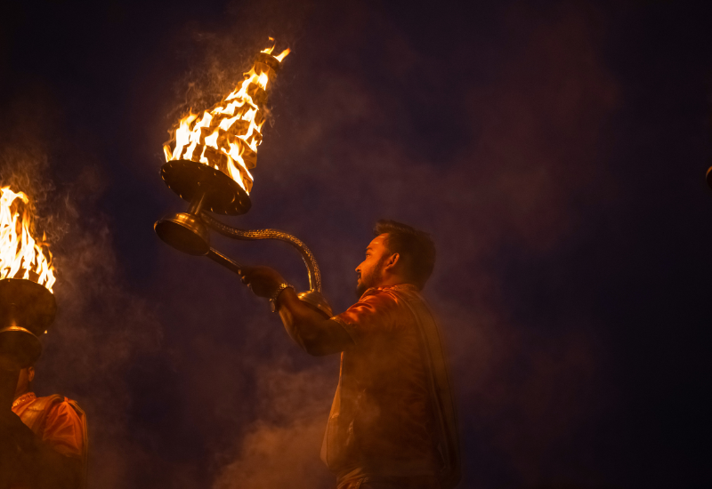 a hindu person doing aarti or praying with lamps