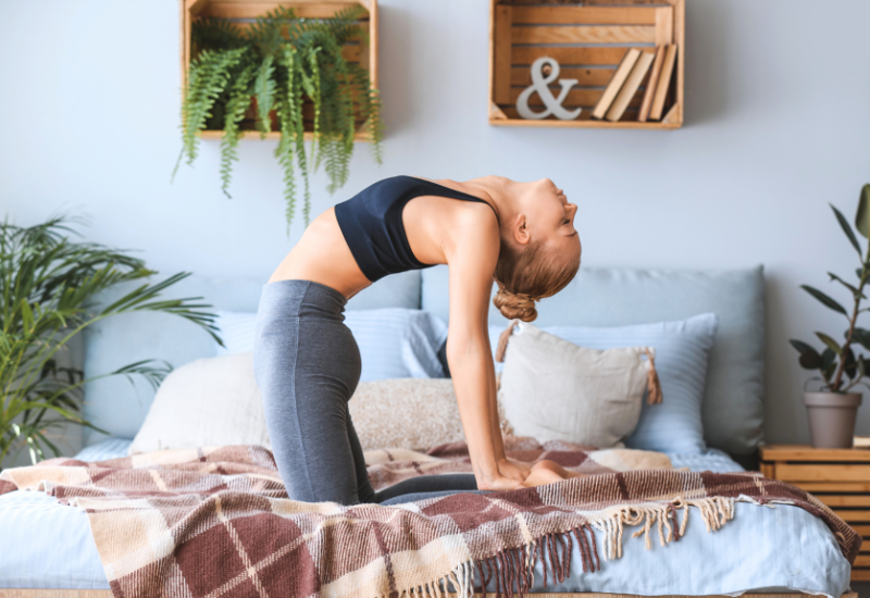 a girl doing camel's pose on the bed