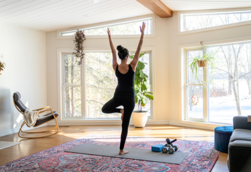 a woman practicing yoga at home when its snowing outside