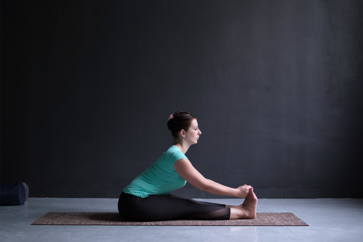 a girl doing seated forward bend to find relief from cold, flu, and influenza