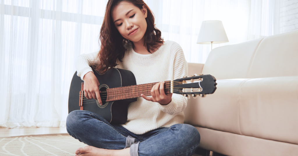 Person playing guitar indoors, casual setting