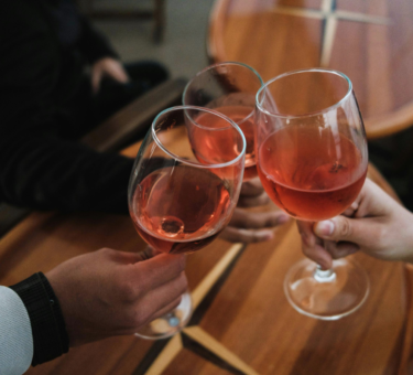 people clanking glasses filled with alcoholic drinks