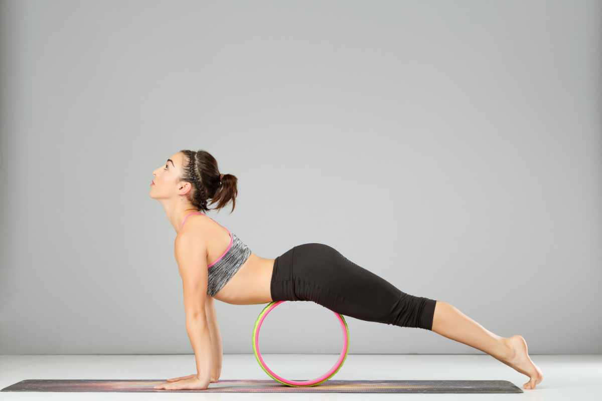 a girl doing upward facing plank using yoga wheel